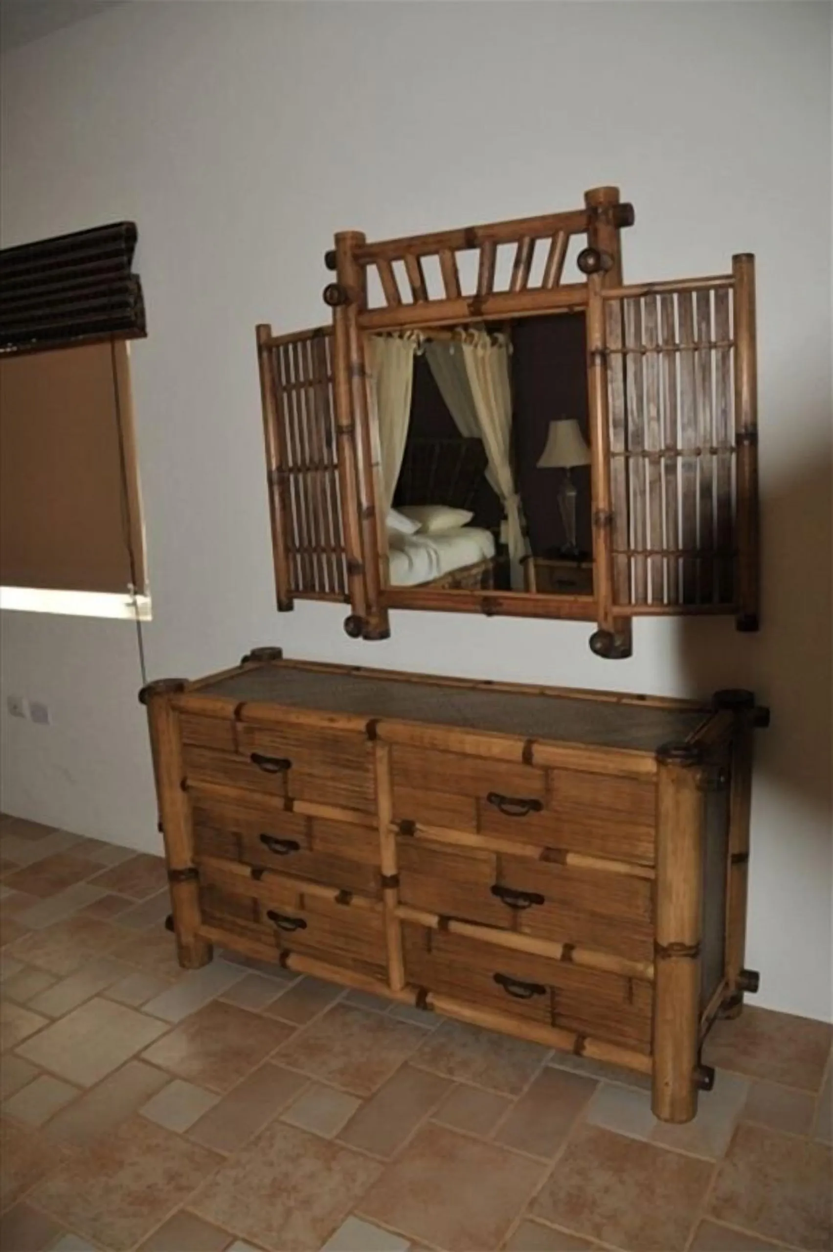 Wooden dresser with drawers and a framed mirror above it in one of the villa bedrooms