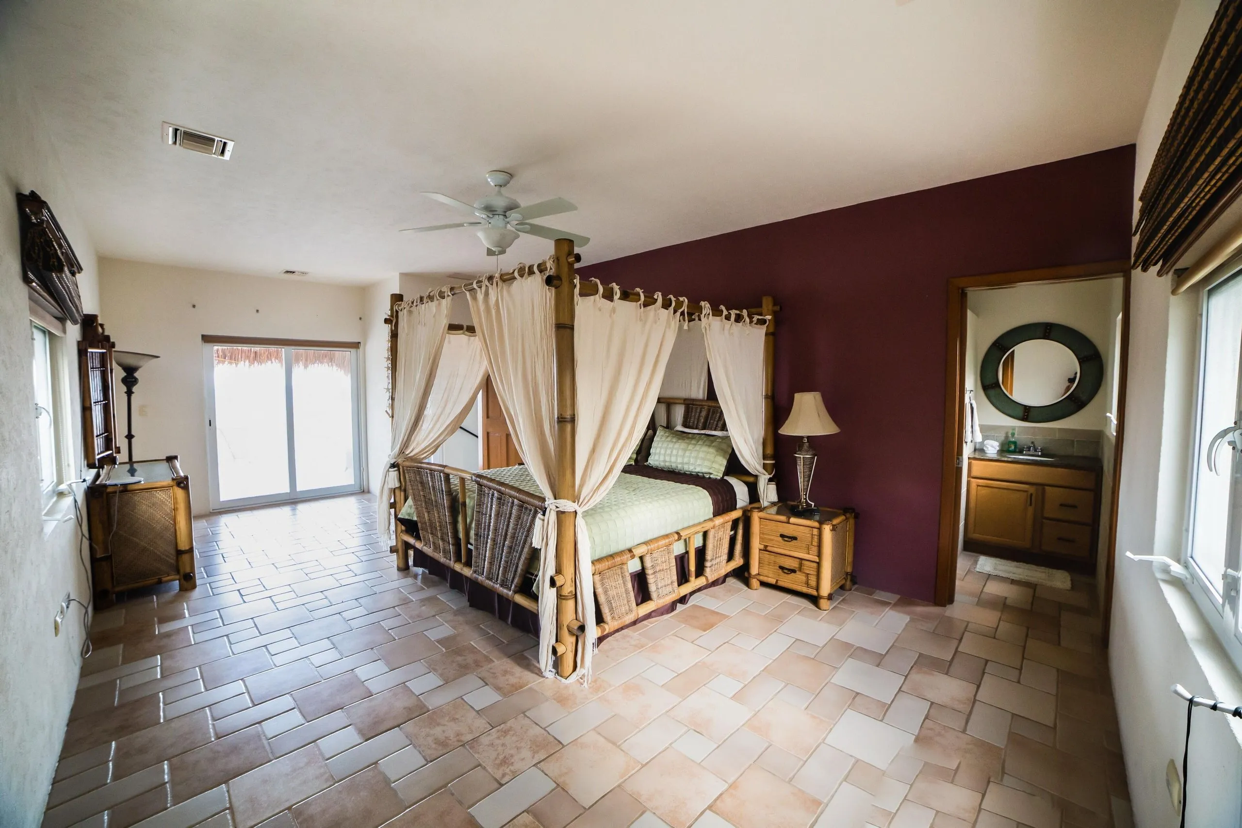 Four-poster king bed with ceiling fan and a large window looking out over the grounds