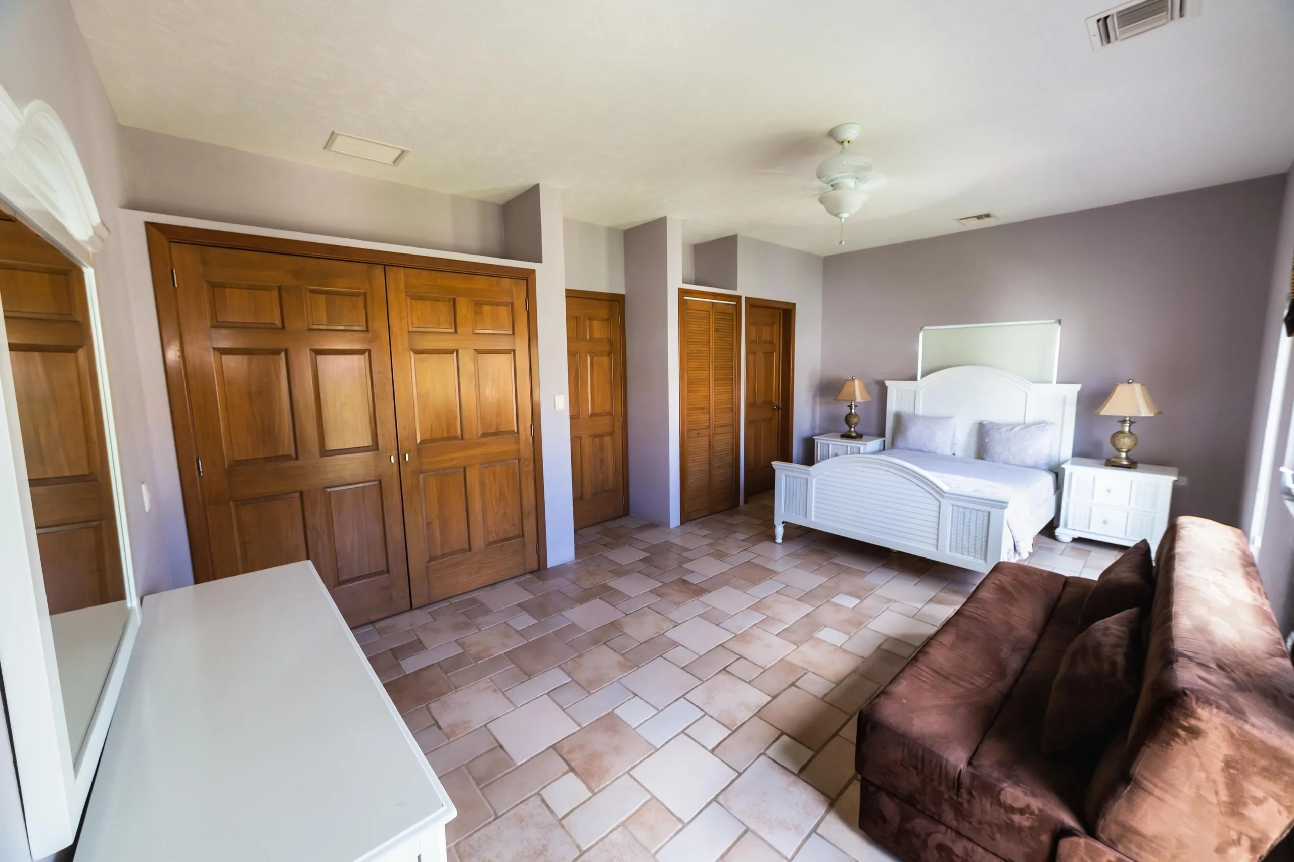 The Safari Room with a queen bed, nightstands, dresser and a brown sofa