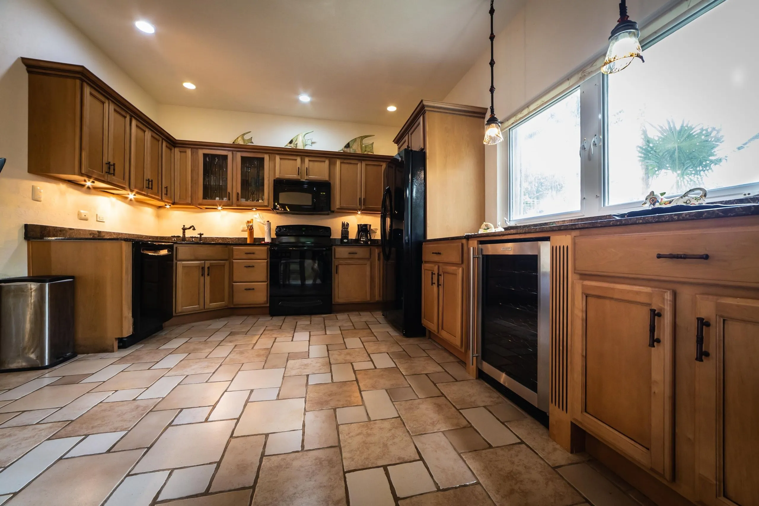 Kitchen corner with microwave, refrigerator and a window letting in natural light