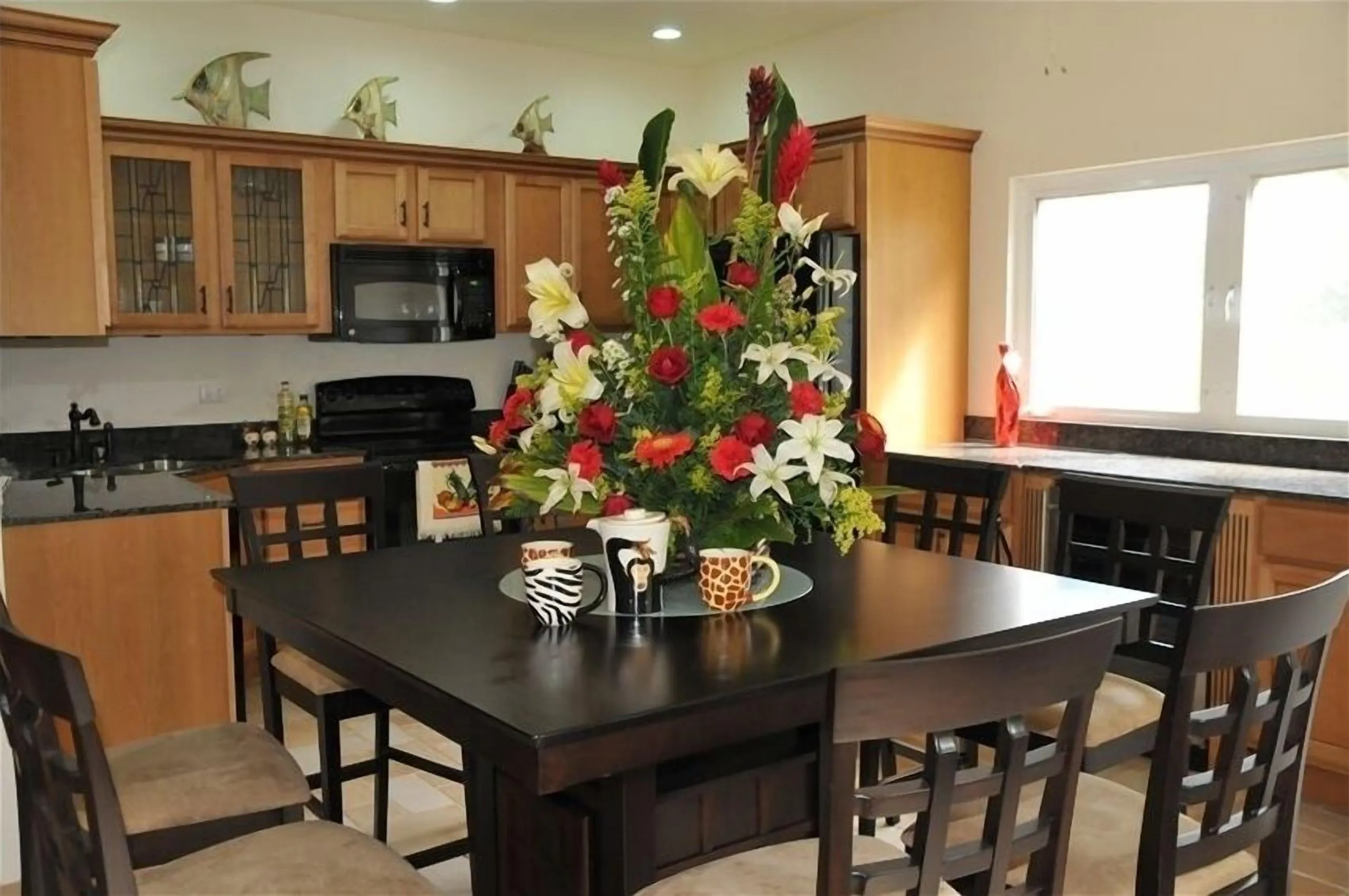 Kitchen and dining table with chairs and a floral centrepiece, beside the granite work surface