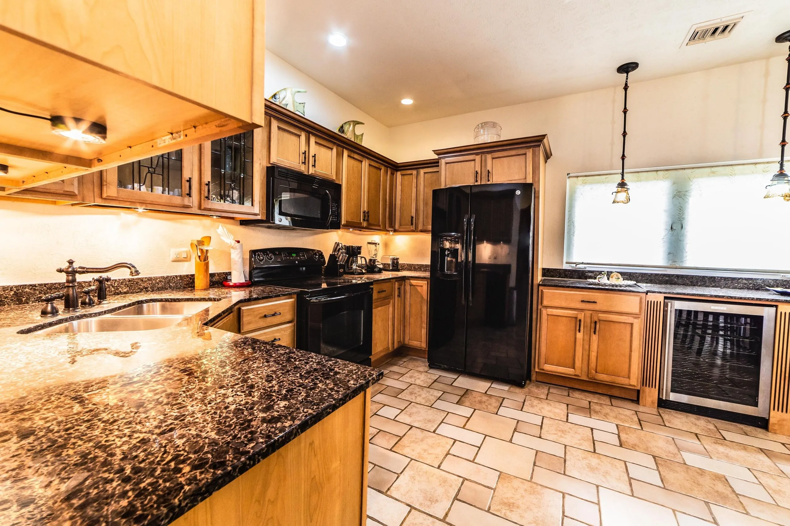 Full kitchen at Casa Dana with granite countertops, wooden cabinets, refrigerator and dishwasher