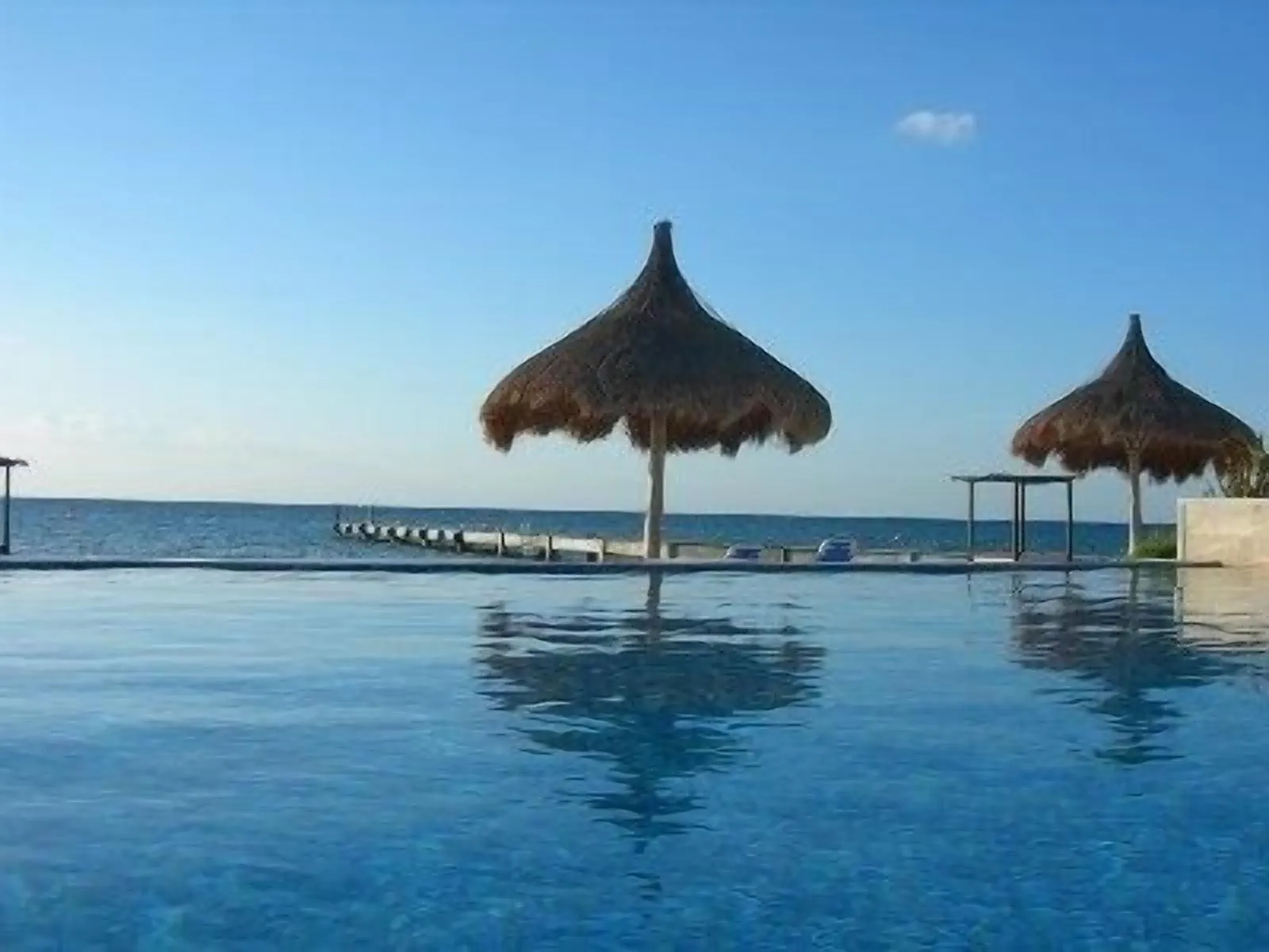 Infinity pool edge meeting the horizon of a calm Caribbean sea under a clear sky